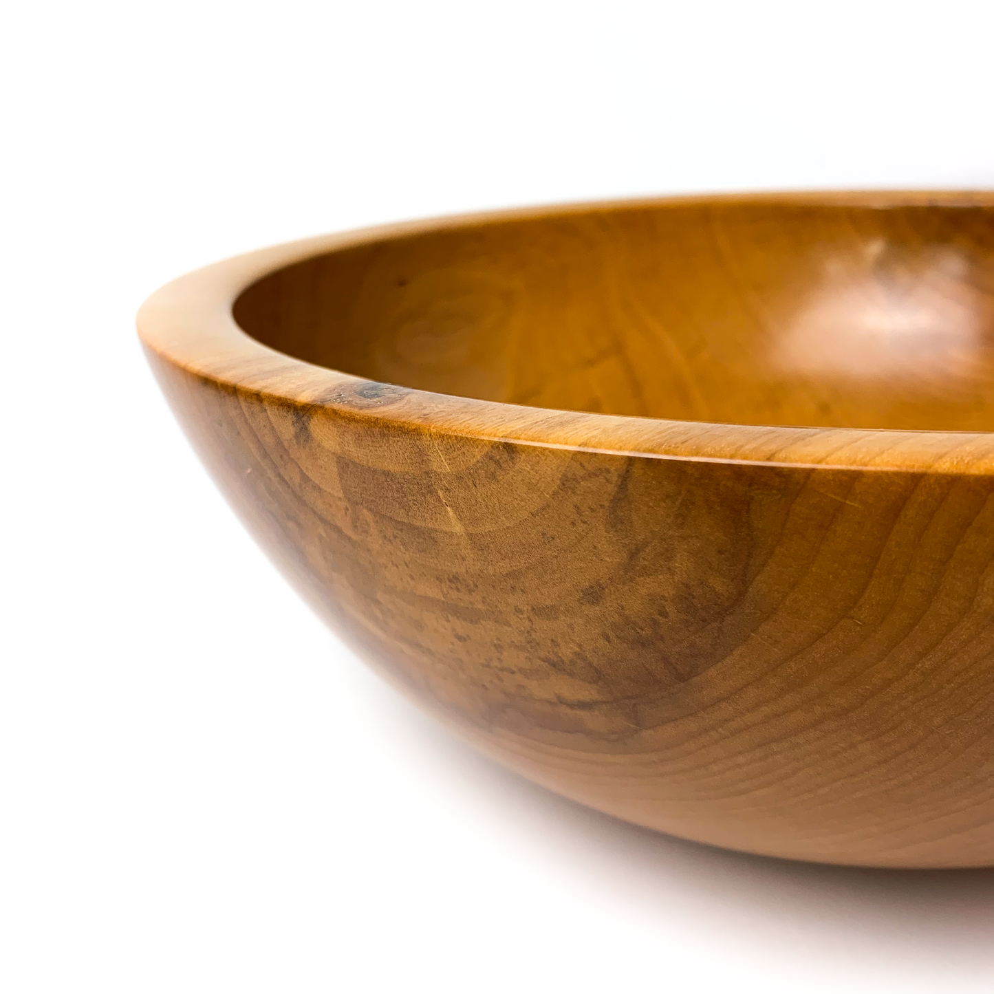 A light brown maple salad bowl, close-up angled view.