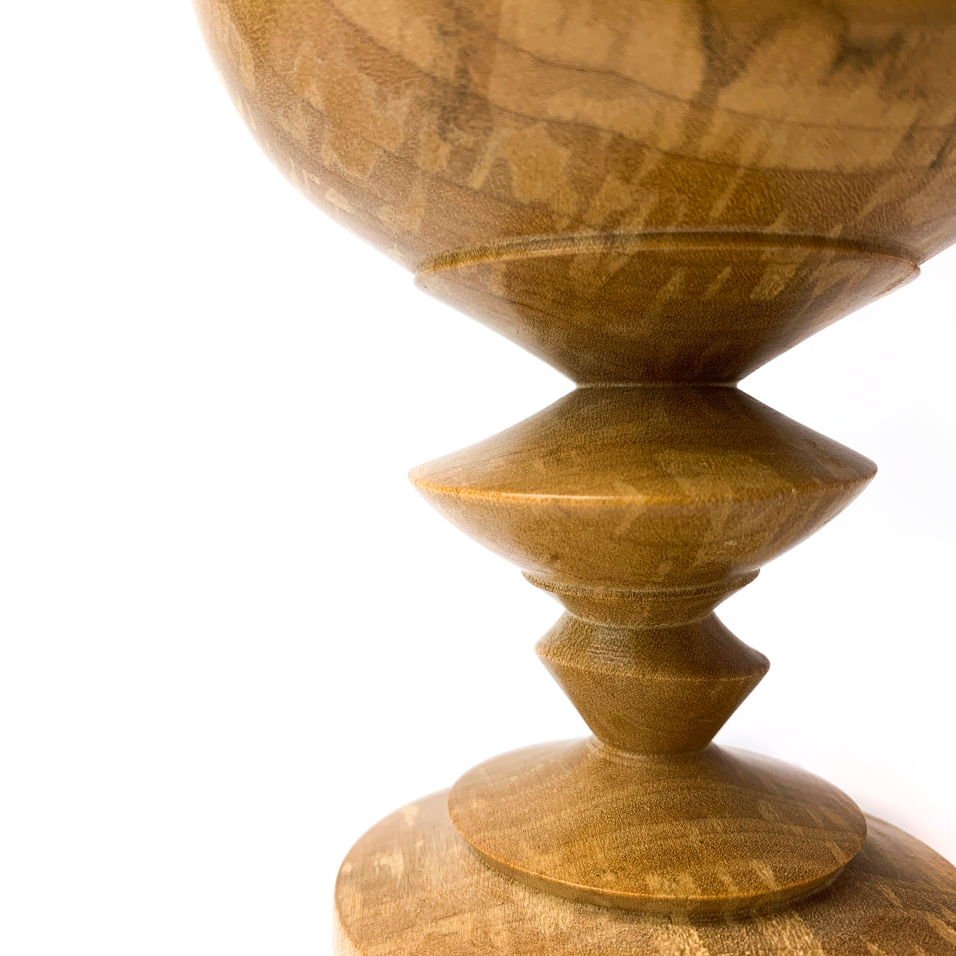 A close-up of a turned wooden goblet with a round bowl, a segmented stem, and a wide base.