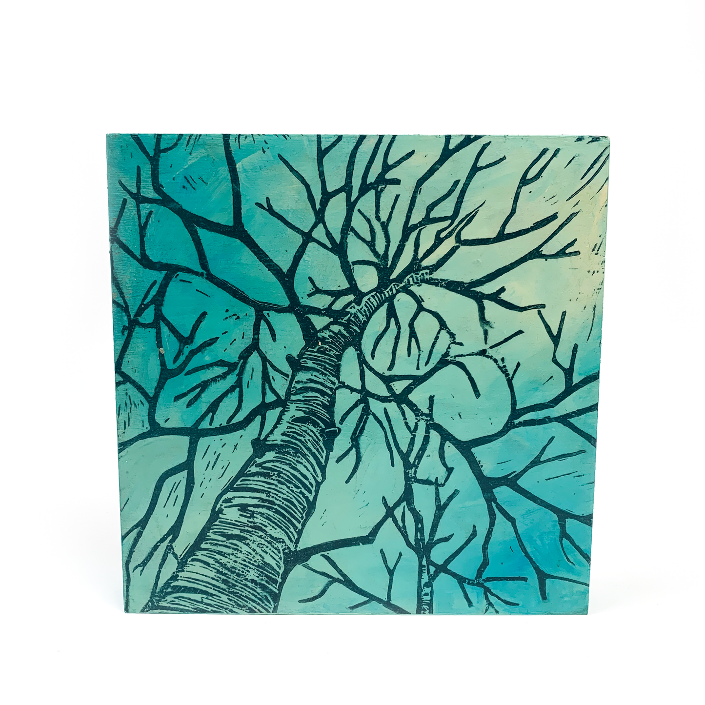 Linocut on wood panel wall hanging: tree branches reaching upwards, evoking vulnerability.