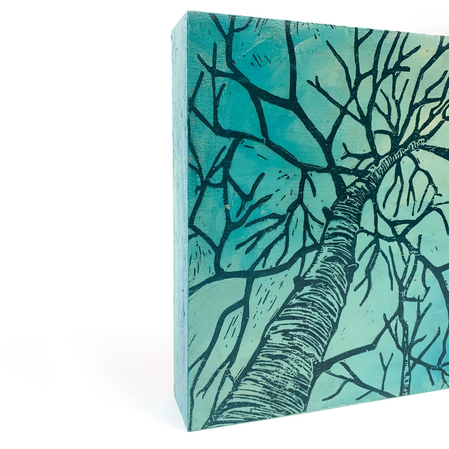 Side view of a square wood panel wall hanging with a tree linocut print, showcasing texture and depth.