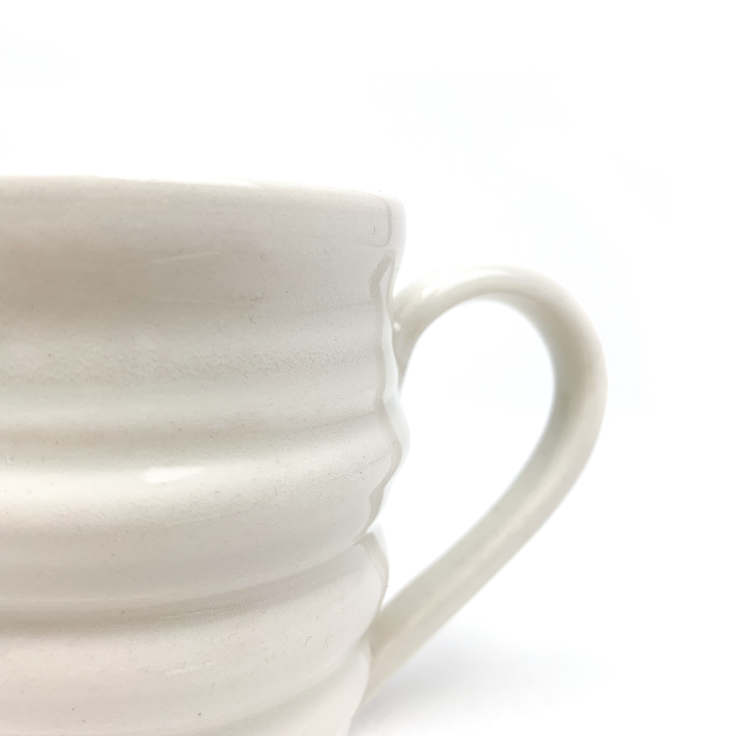 Close-up of a ceramic mug, showing its textured, horizontally ridged surface and a portion of its curved handle.