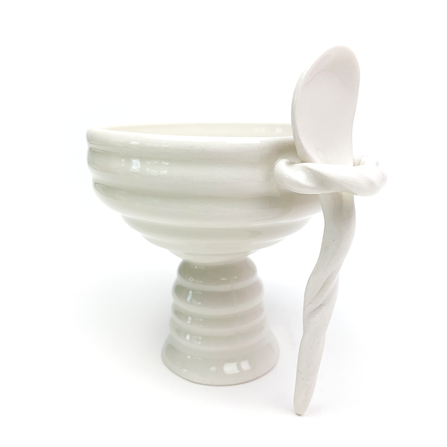 A ceramic ice cream bowl with horizontal ridges on the bowl and pedestal, featuring a matching spoon held by a twisted handle.