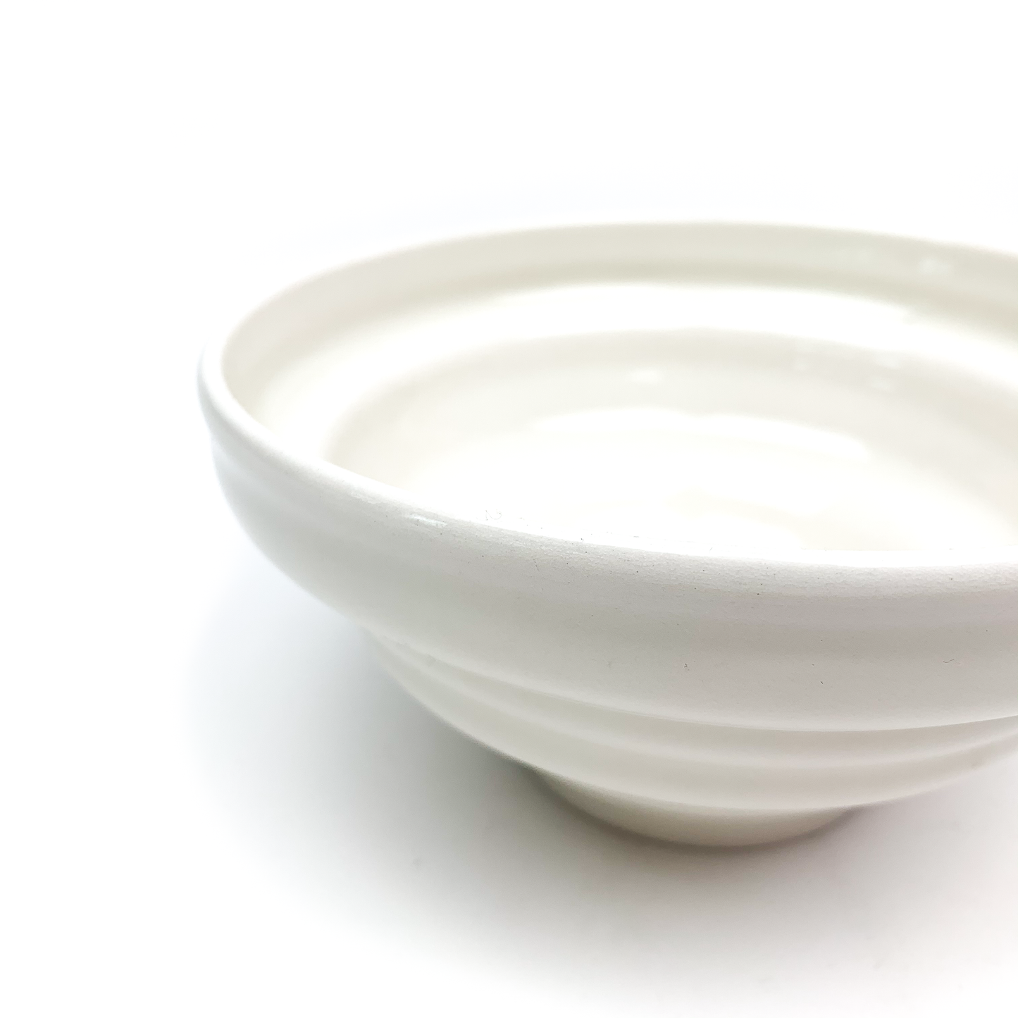 A close-up of a ceramic bowl showing its wide, smooth rim and the textured horizontal ridges forming its shape.