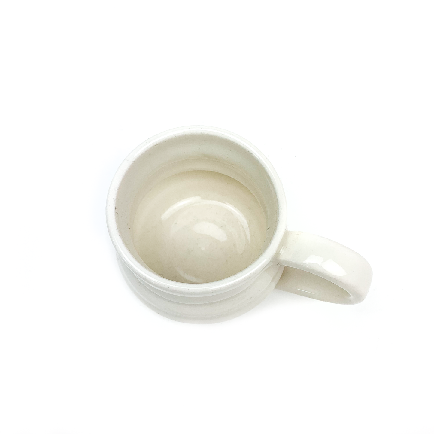 Overhead view of a ceramic mug with horizontal ridges and a curved handle, showing its smooth interior.