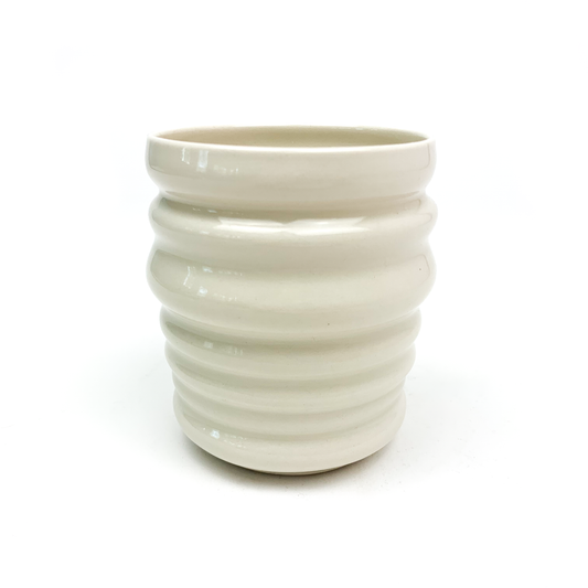 A cylindrical ceramic cup with evenly spaced horizontal ridges wrapping around its body.