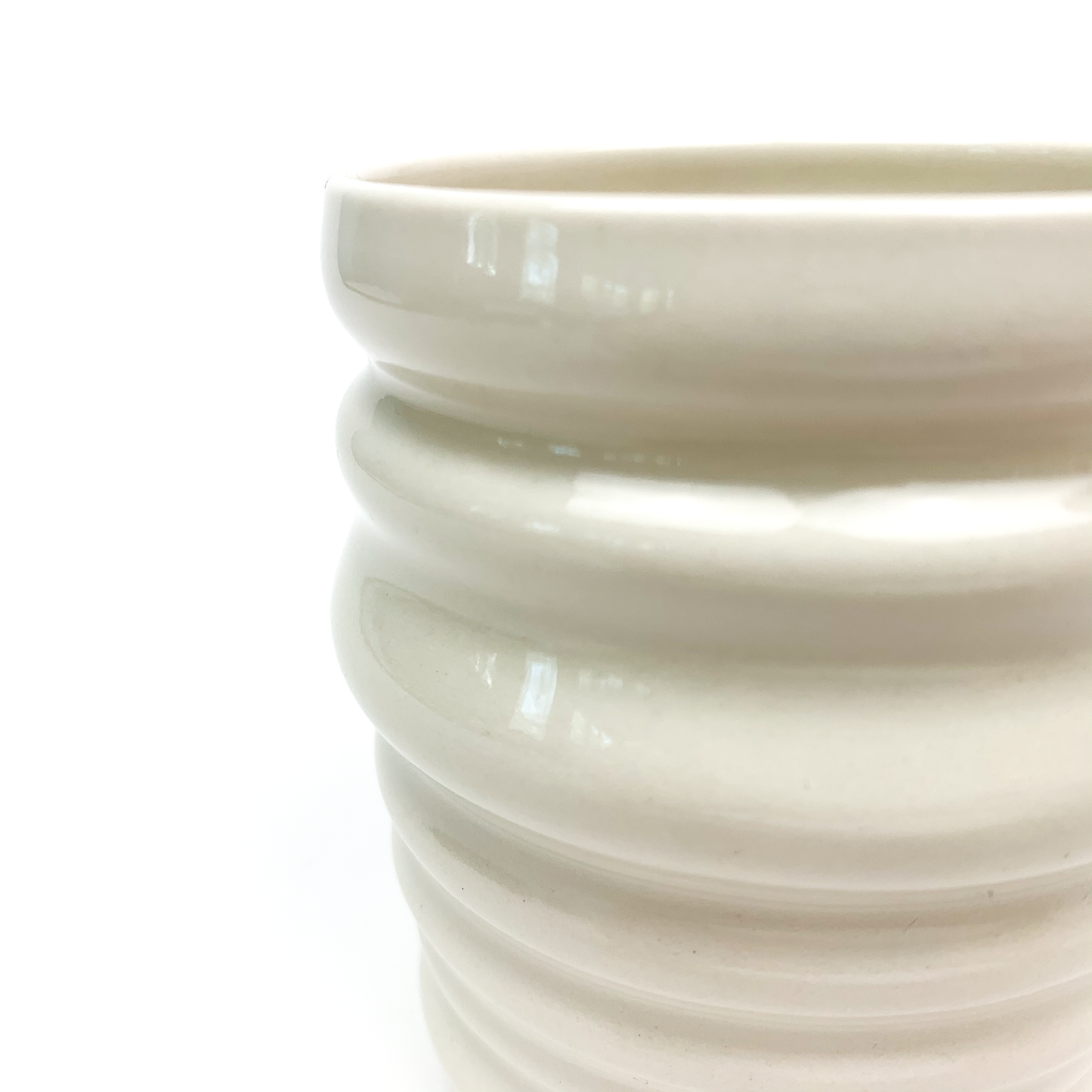 Close-up of a ceramic cup showing its smooth rim and textured, ridged outer surface.