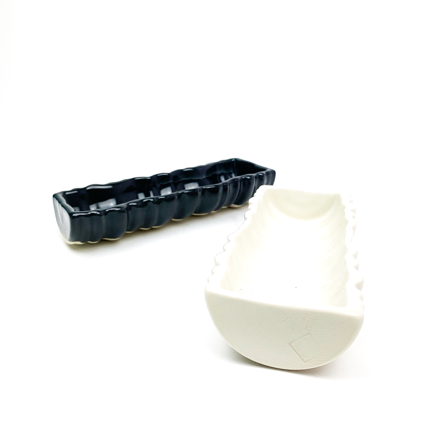 Two ceramic planters: a long, dark, ridged rectangular one and a shorter, light, ridged oval one.