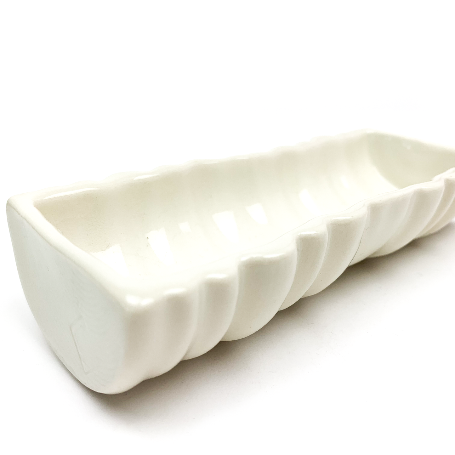 A long, rectangular ceramic dish or planter with a wavy, ridged outer surface.
