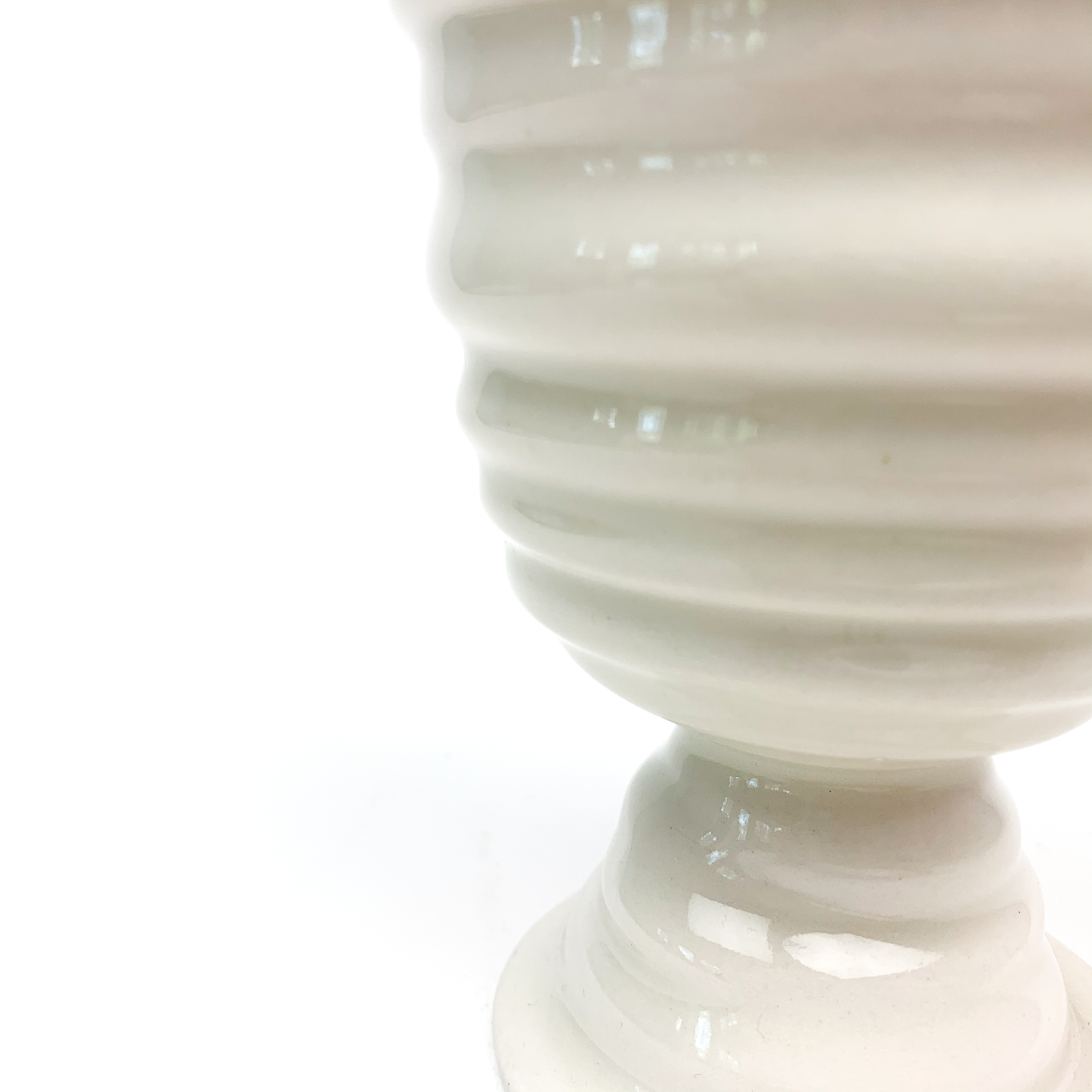 Partial view of a ceramic goblet, highlighting the textured horizontal ridges on its bowl and the top of its stem.