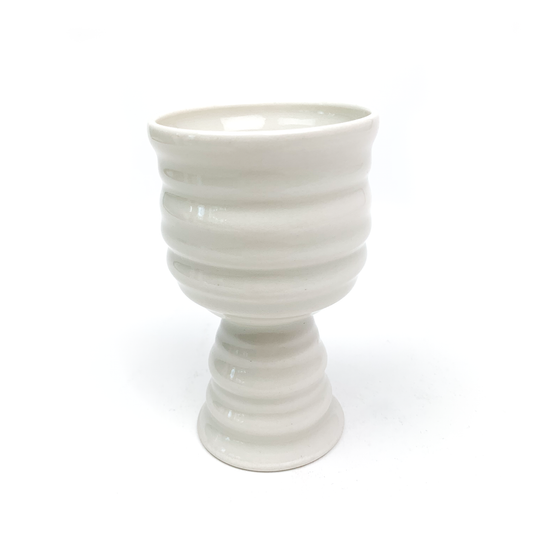 A handcrafted ceramic goblet with horizontal ridges on the bowl and stem, flaring slightly at the base.