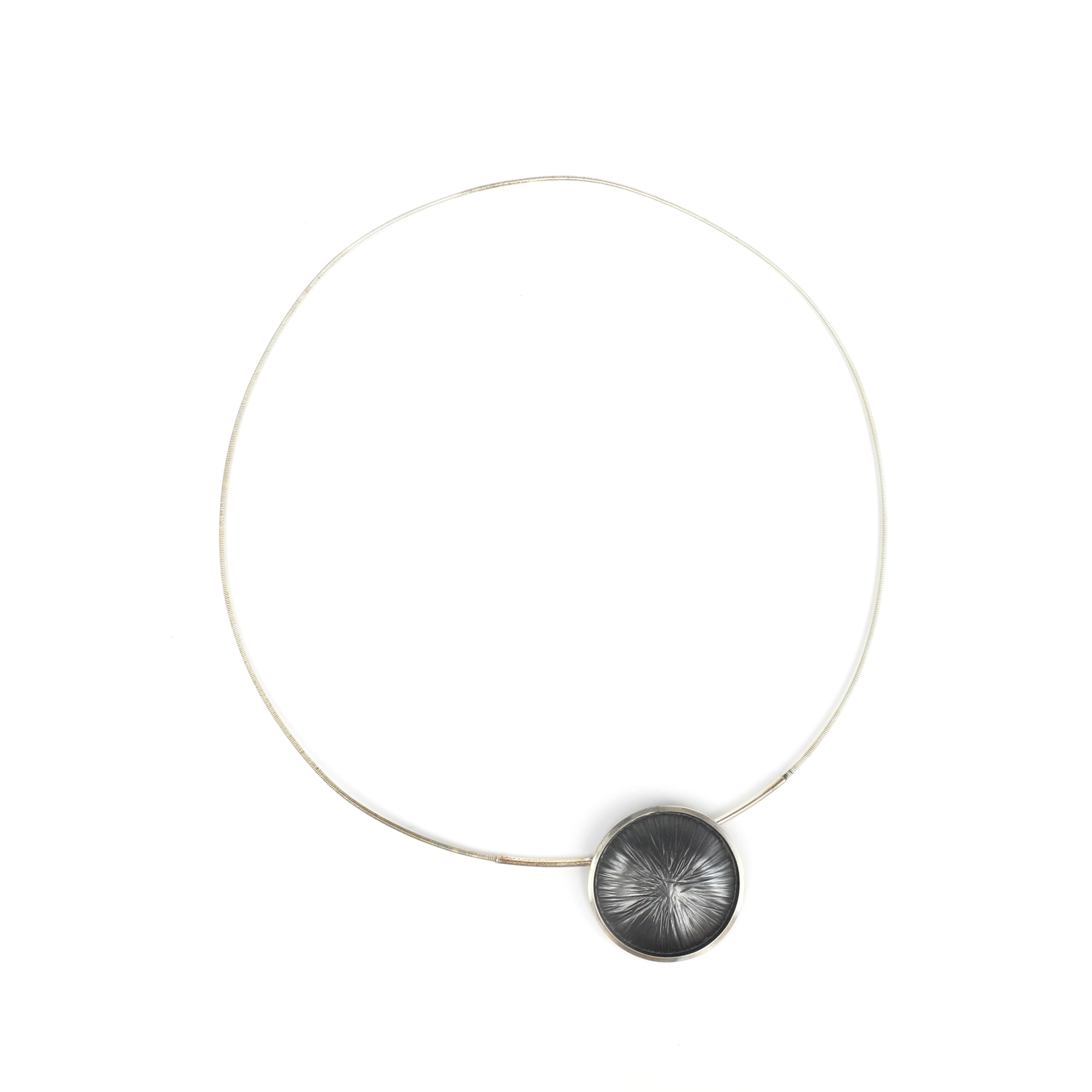 A silver wire necklace features a round, dark pendant with radiating lines and a small blue accent bead.