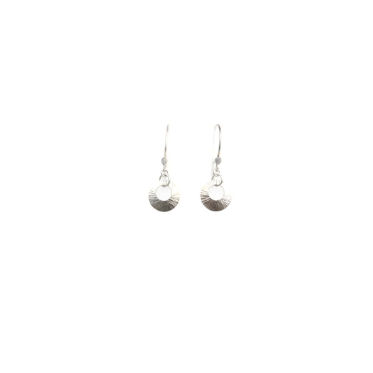 Two silver beam earrings with a circular cutout hang from silver hooks.