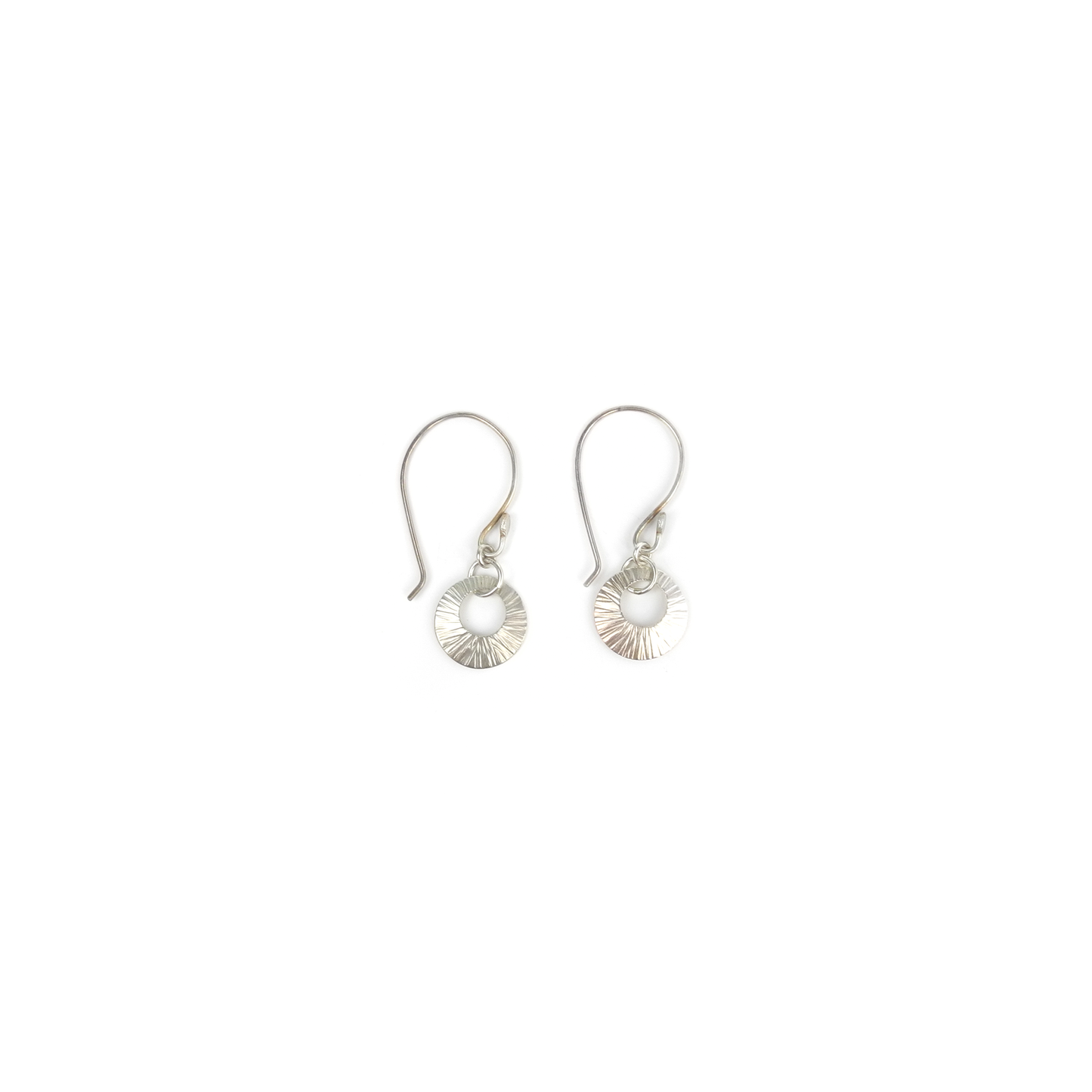 Two silver earrings with a circular cutout and radiating lines hang from silver hooks.