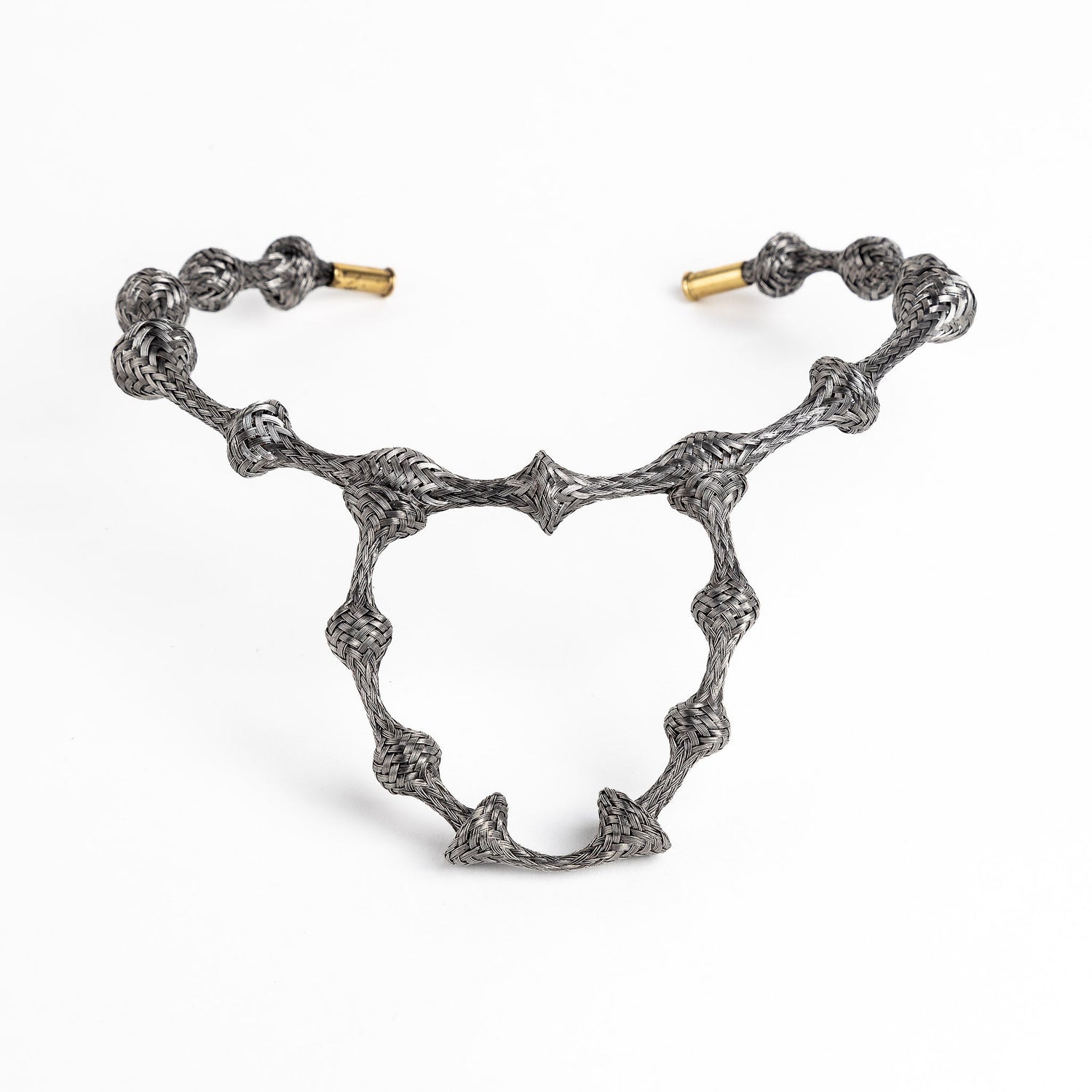 Braided stainless steel cuff bracelet with gold end caps, curved in a heart shape, on white.