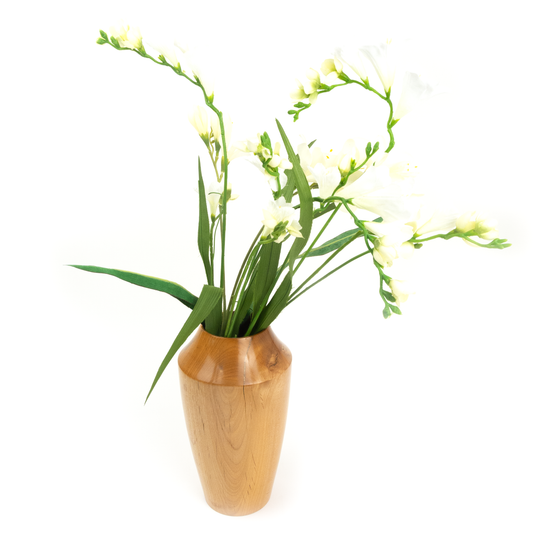 A light brown wooden vase with white freesia flowers.