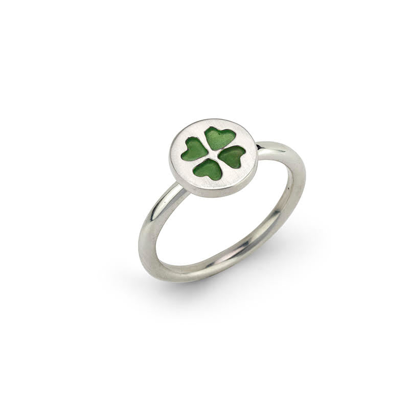 Silver ring with a round setting featuring a green four-leaf clover.