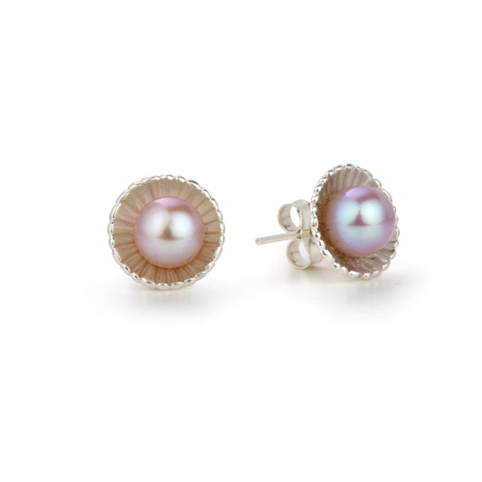 Two pearl stud earrings, each featuring a iridescent pearl in a scalloped silver setting.