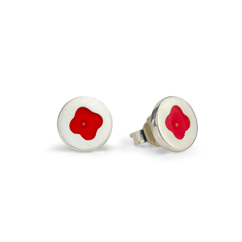 Two silver stud earrings, each with a round, light setting and a stylized red flower with a tiny center.