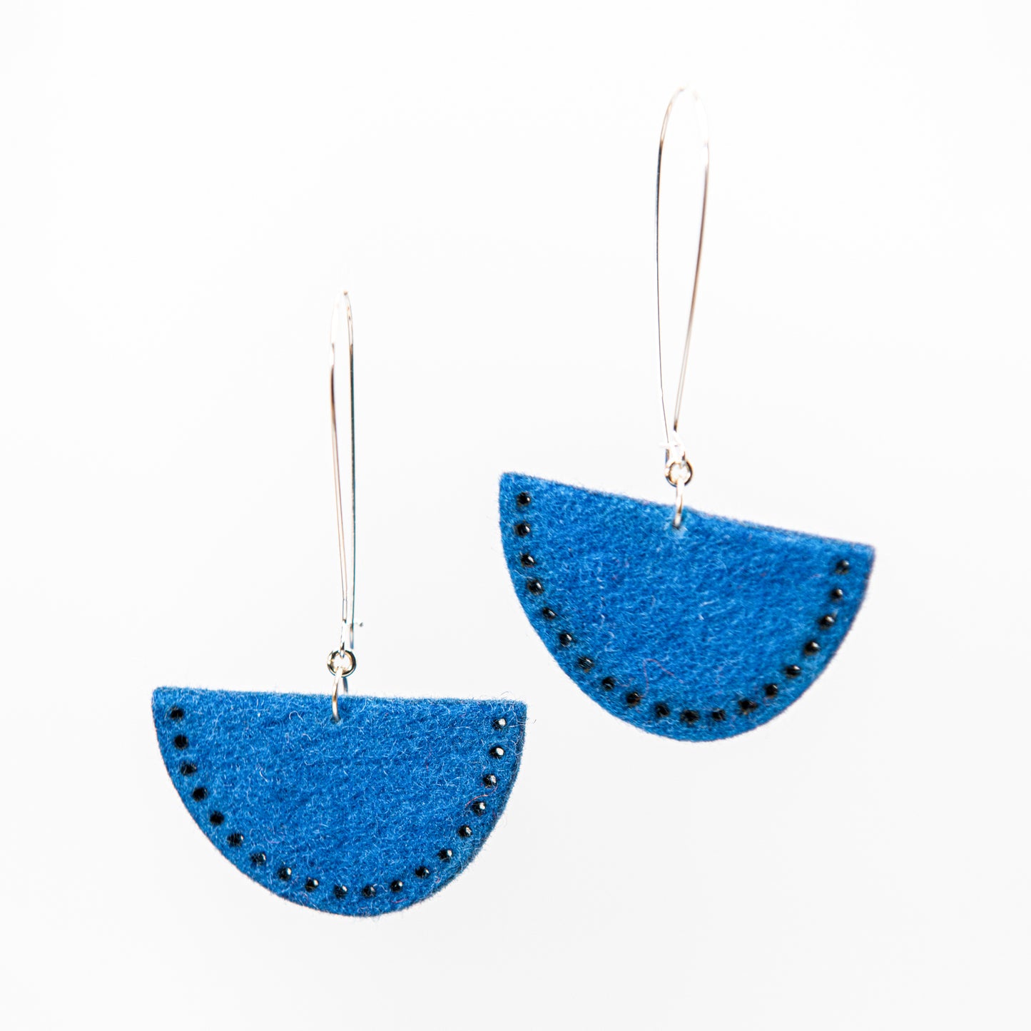 Two blue semi-circular earrings with small dark accents hang from silver hooks.
