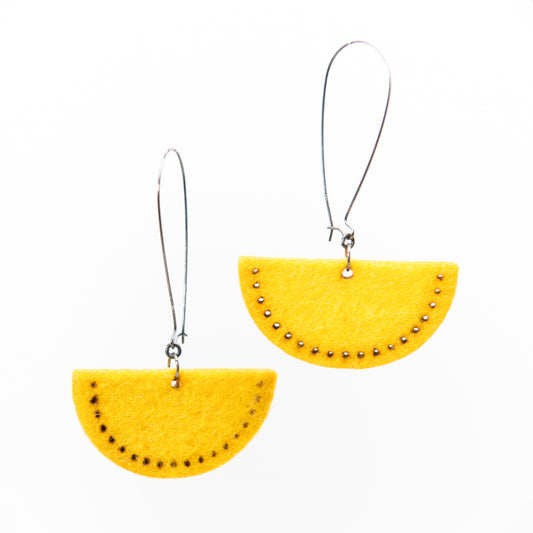 Two yellow semi-circular earrings with small dark accents hang from silver hooks.