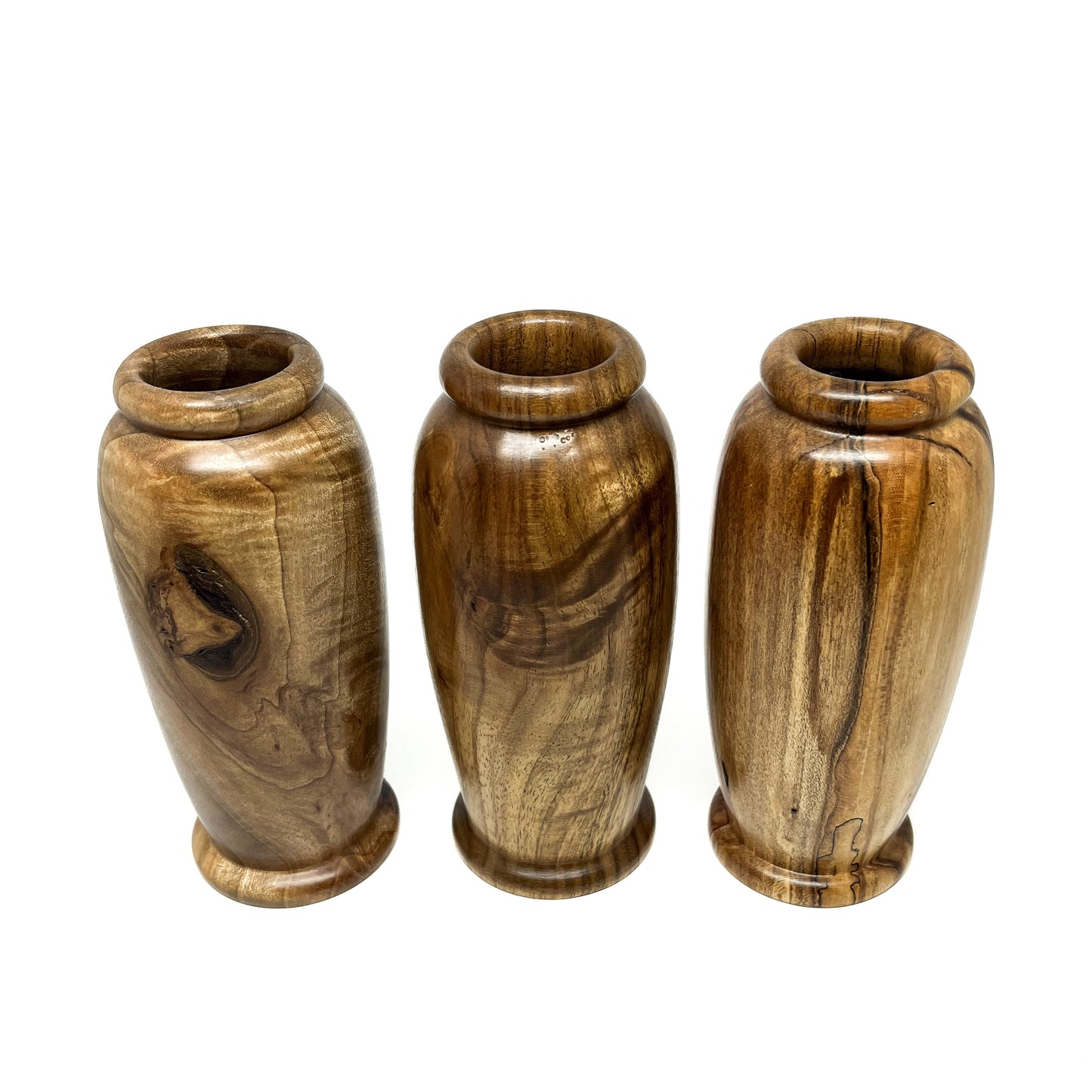 Three small wooden vases with unique natural wood grain patterns and rounded openings, arranged in a row.