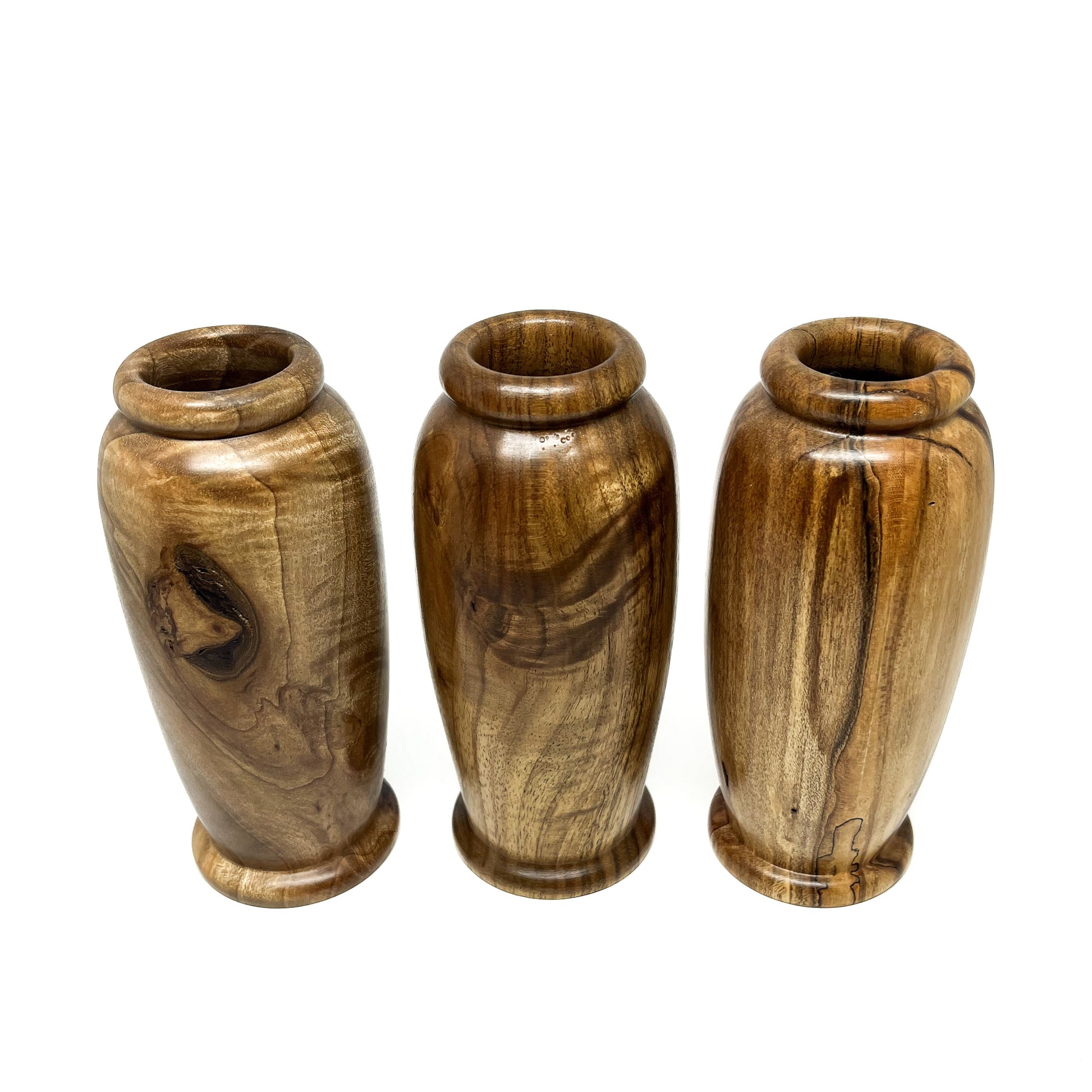 Three small wooden vases with unique natural wood grain patterns and rounded openings, arranged in a row.