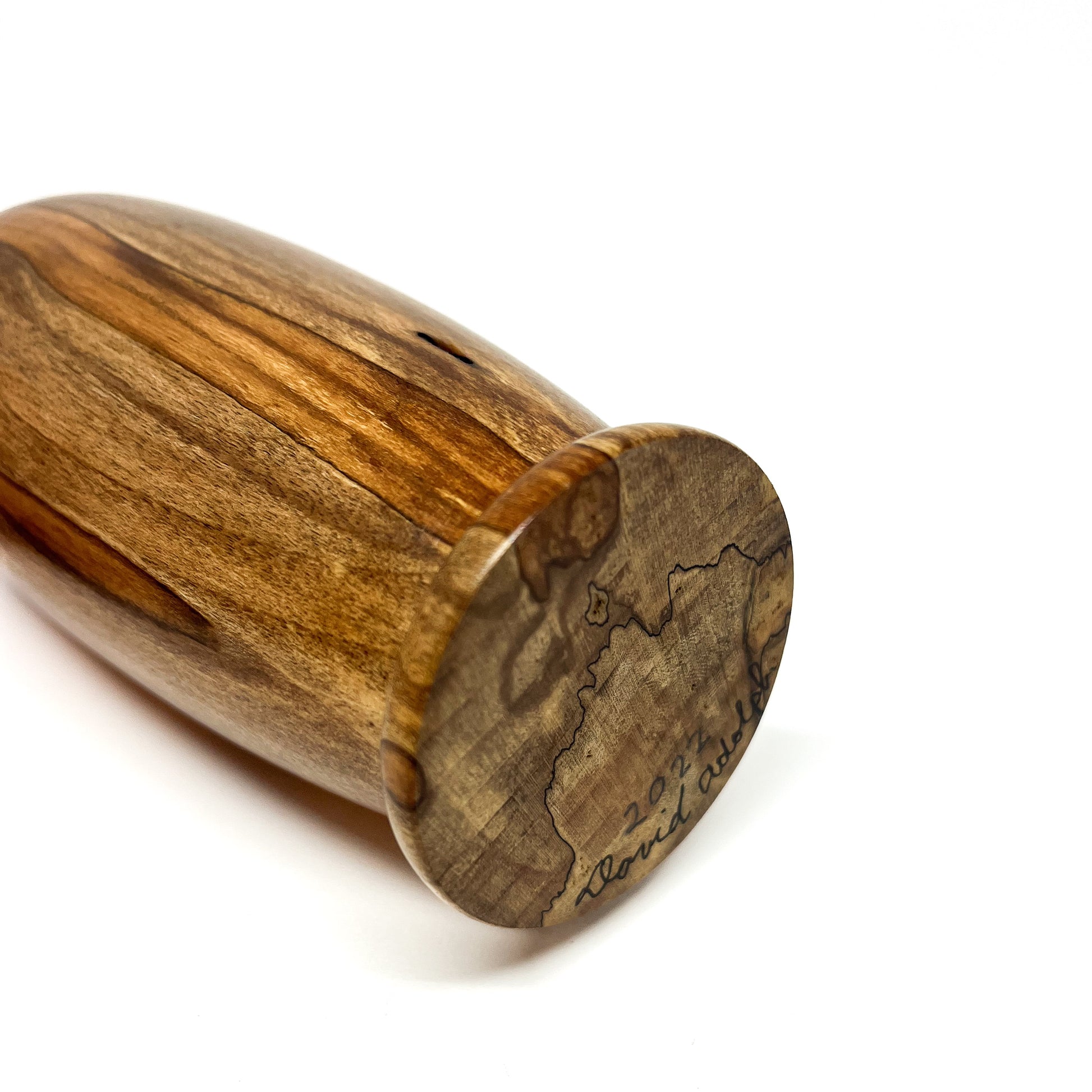 Angled view of a wooden vase lying on its side, showing the base with a signature and "2022".