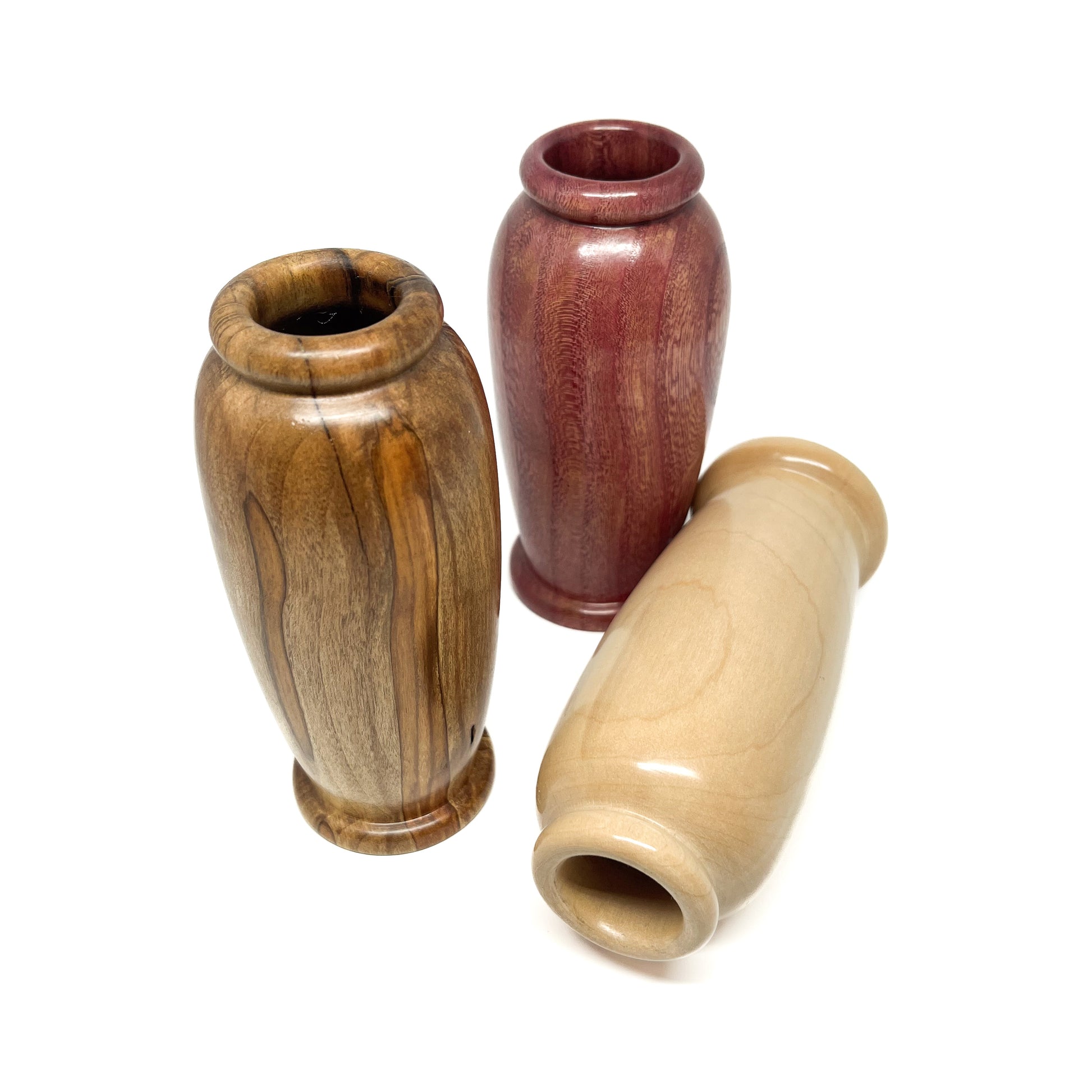 Angled overhead view of three small, polished wooden vases with distinct wood grains and rounded openings.