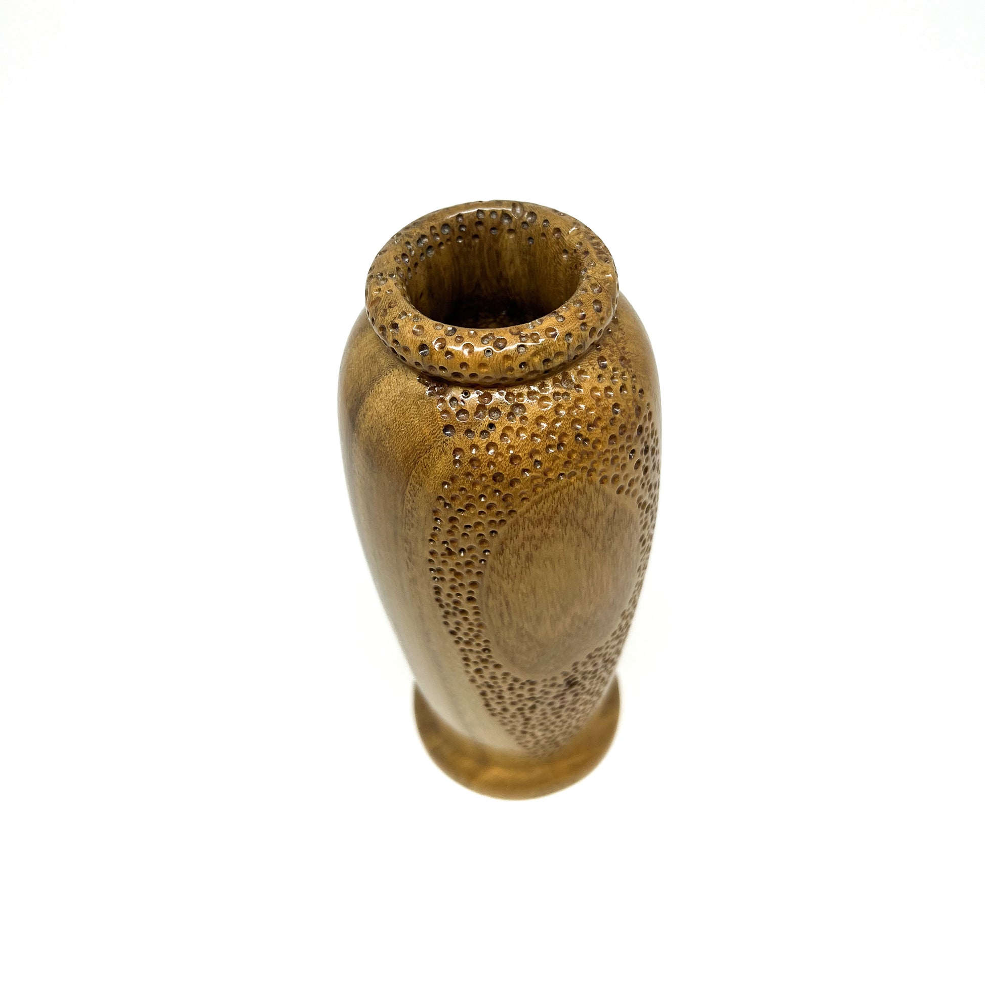 Angled top-down view of a small wooden vase with carved circular patterns and perforations on the body and rim.