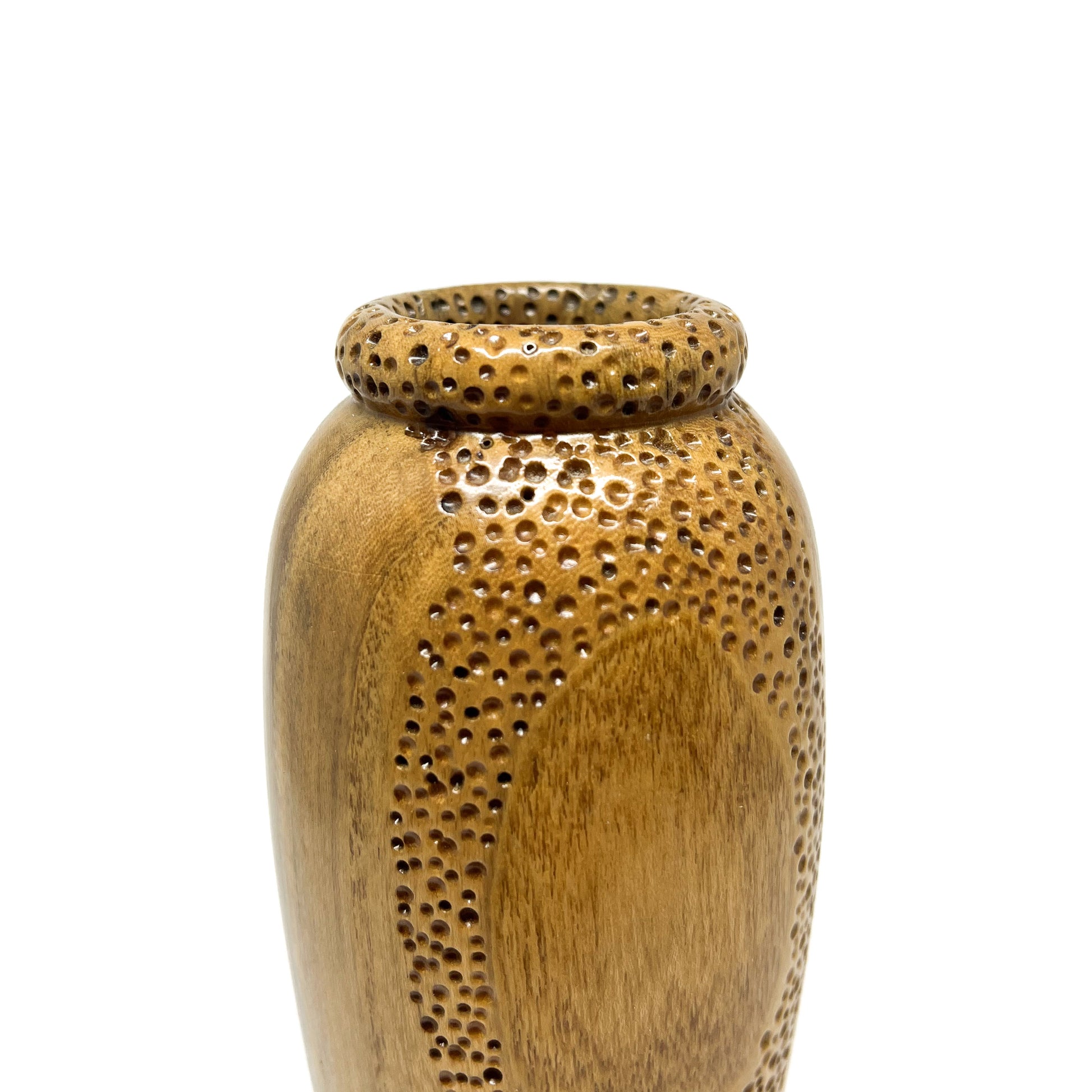 Close-up of a small, textured wood vase with carved circular patterns and small perforations around the opening.