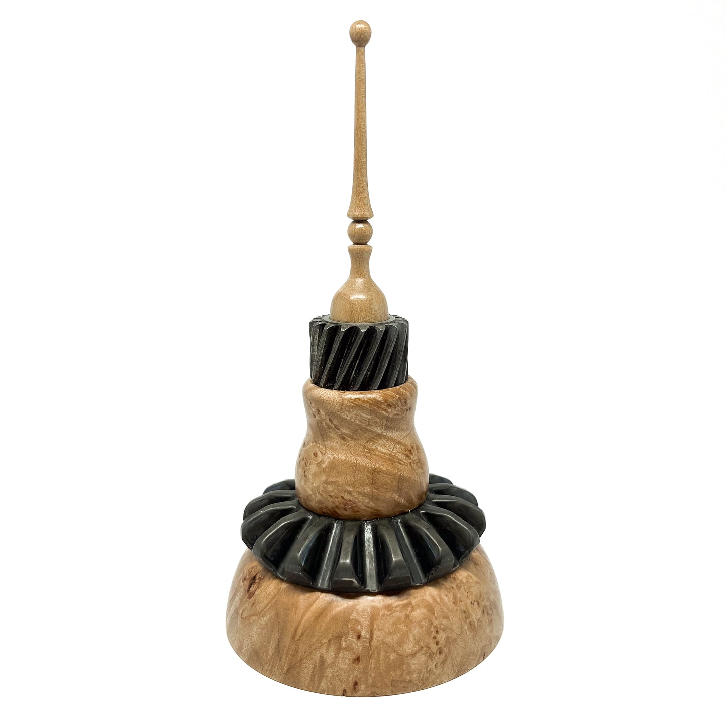 Stacked mixed media spire sculpture with wood, black ridged elements, and a slender, topped spire.