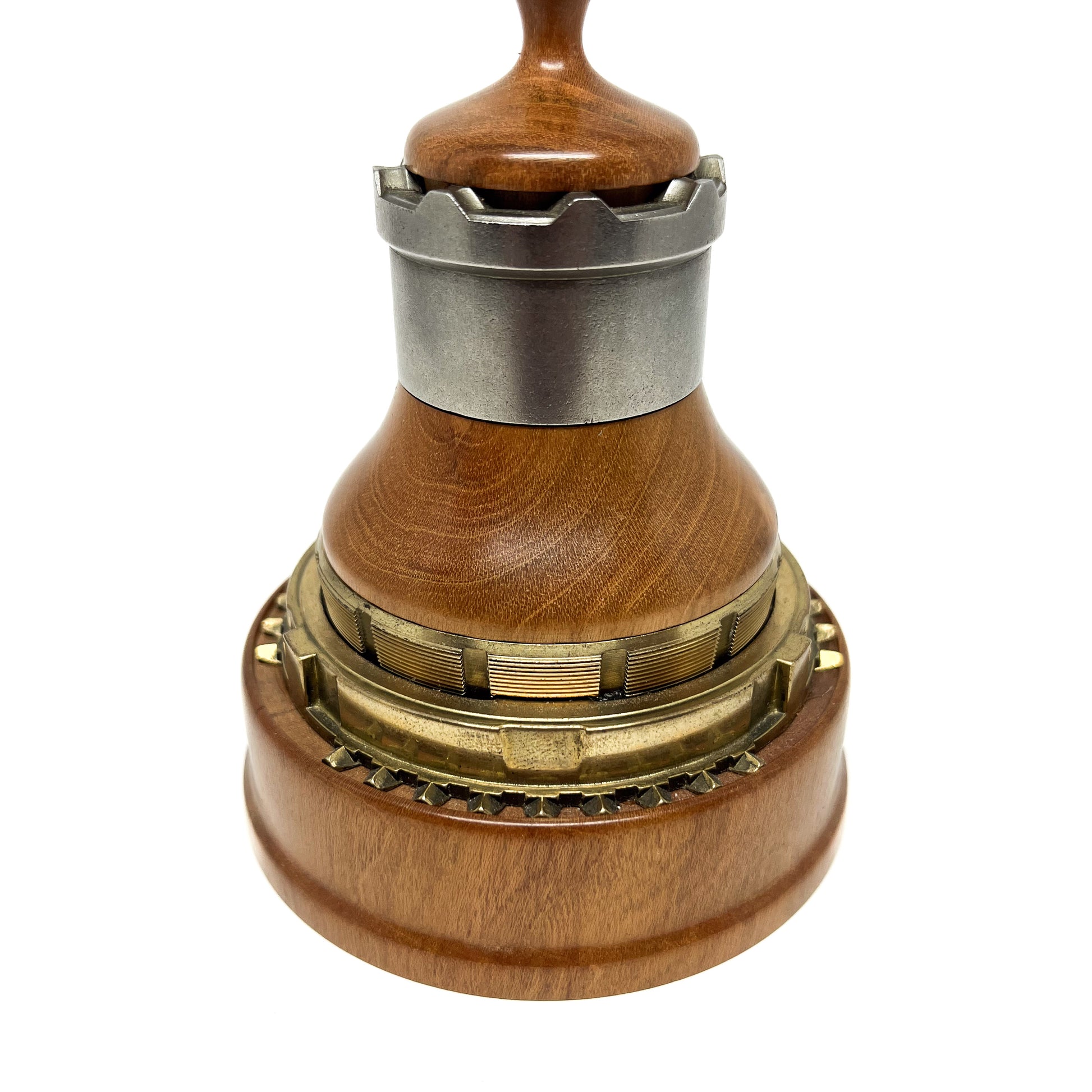 Close-up of a wooden and metal spire sculpture with intricate layered components and a smooth wooden top.
