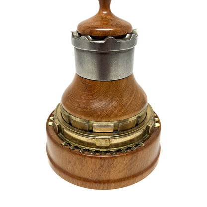 Close-up of a wooden and metal spire sculpture with intricate layered components and a smooth wooden top.