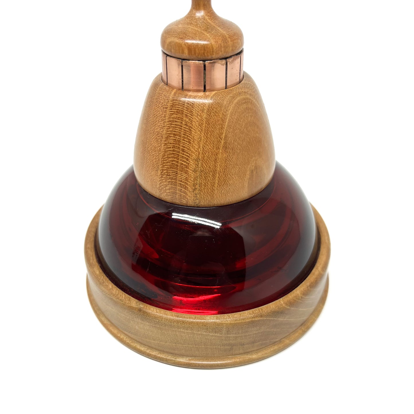 Close-up of a mixed media sculpture with a deep red glass dome, wooden components, and copper vertical strips.