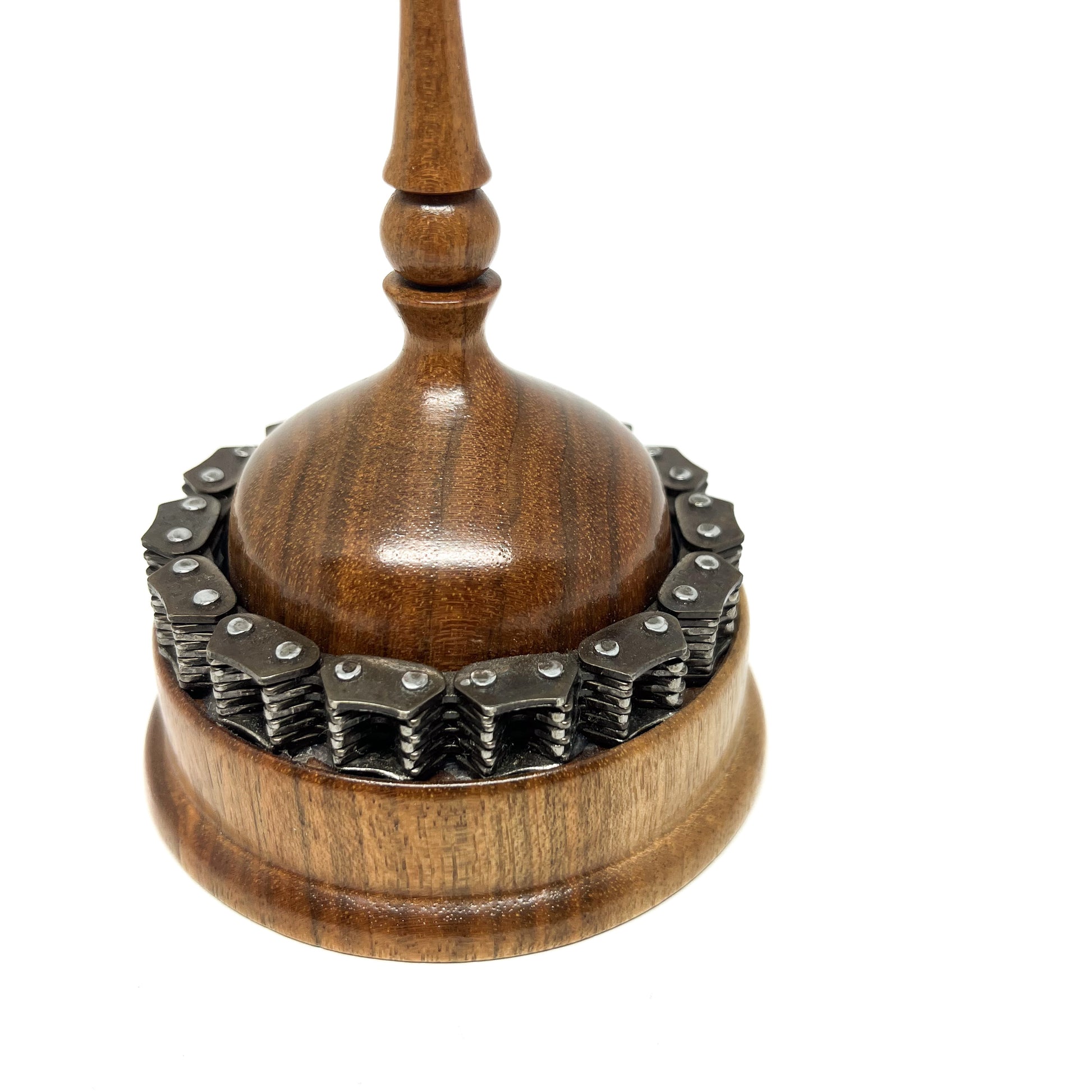 Close-up of a wooden spire sculpture with a detailed chain encircling the base and a smooth, rounded top.