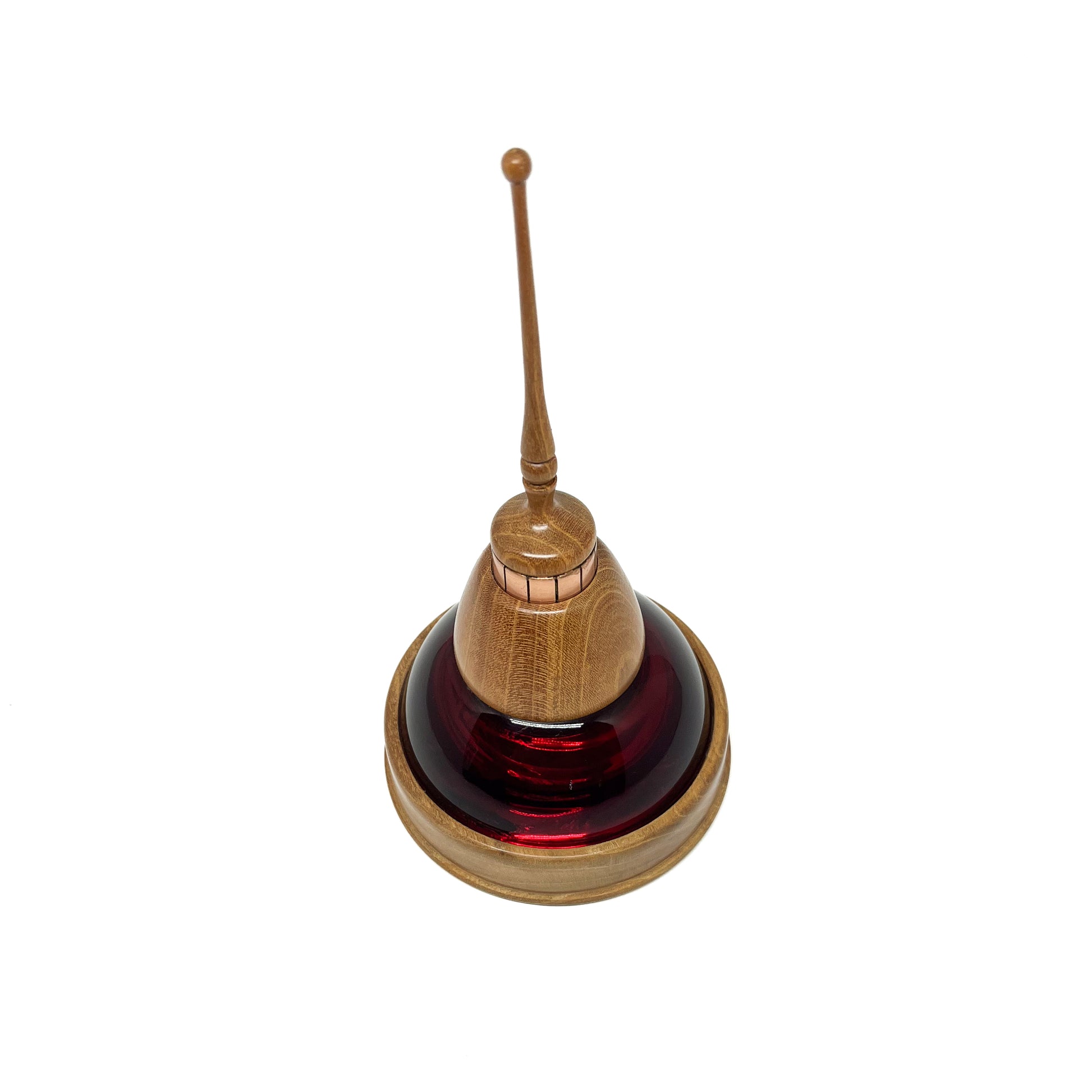Overhead view of a mixed media sculpture with a dark red glass dome, wooden elements, copper details, and a thin spire.
