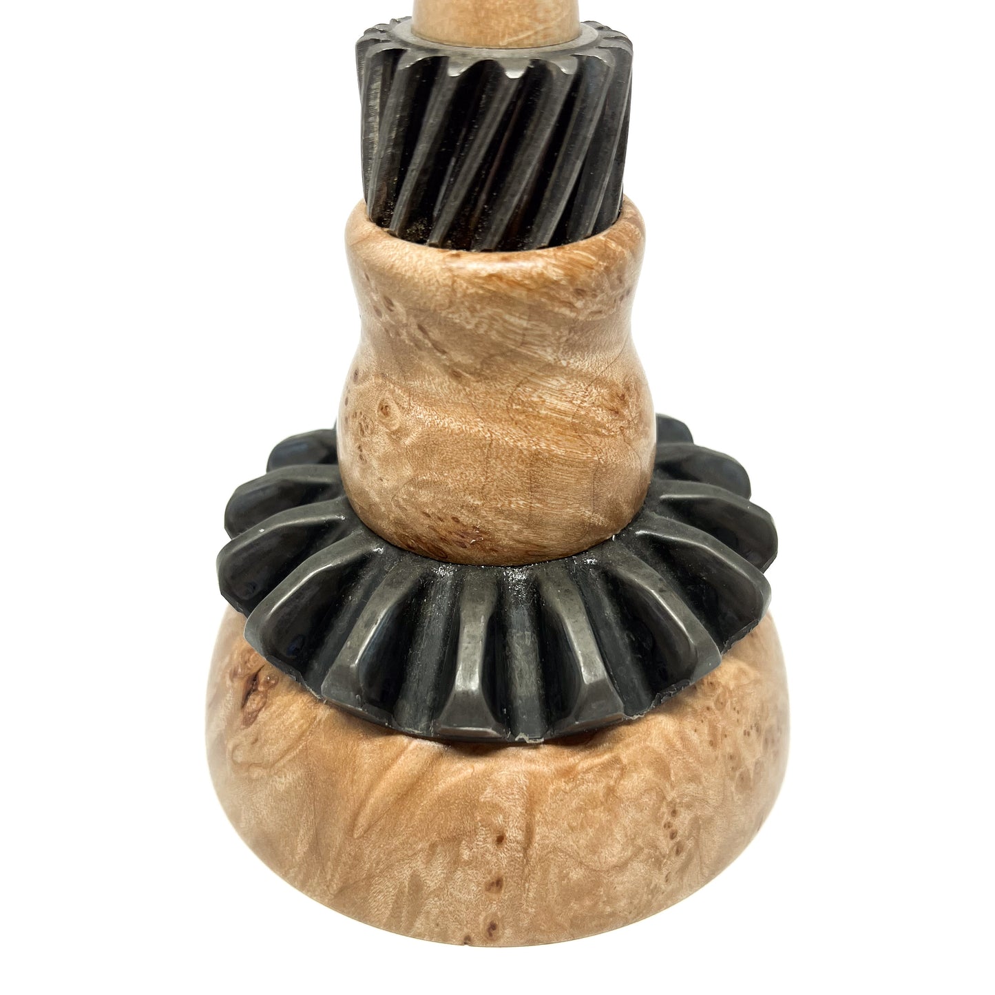 Close-up of a stacked mixed media spire sculpture with textured wood and black, ridged metal components.