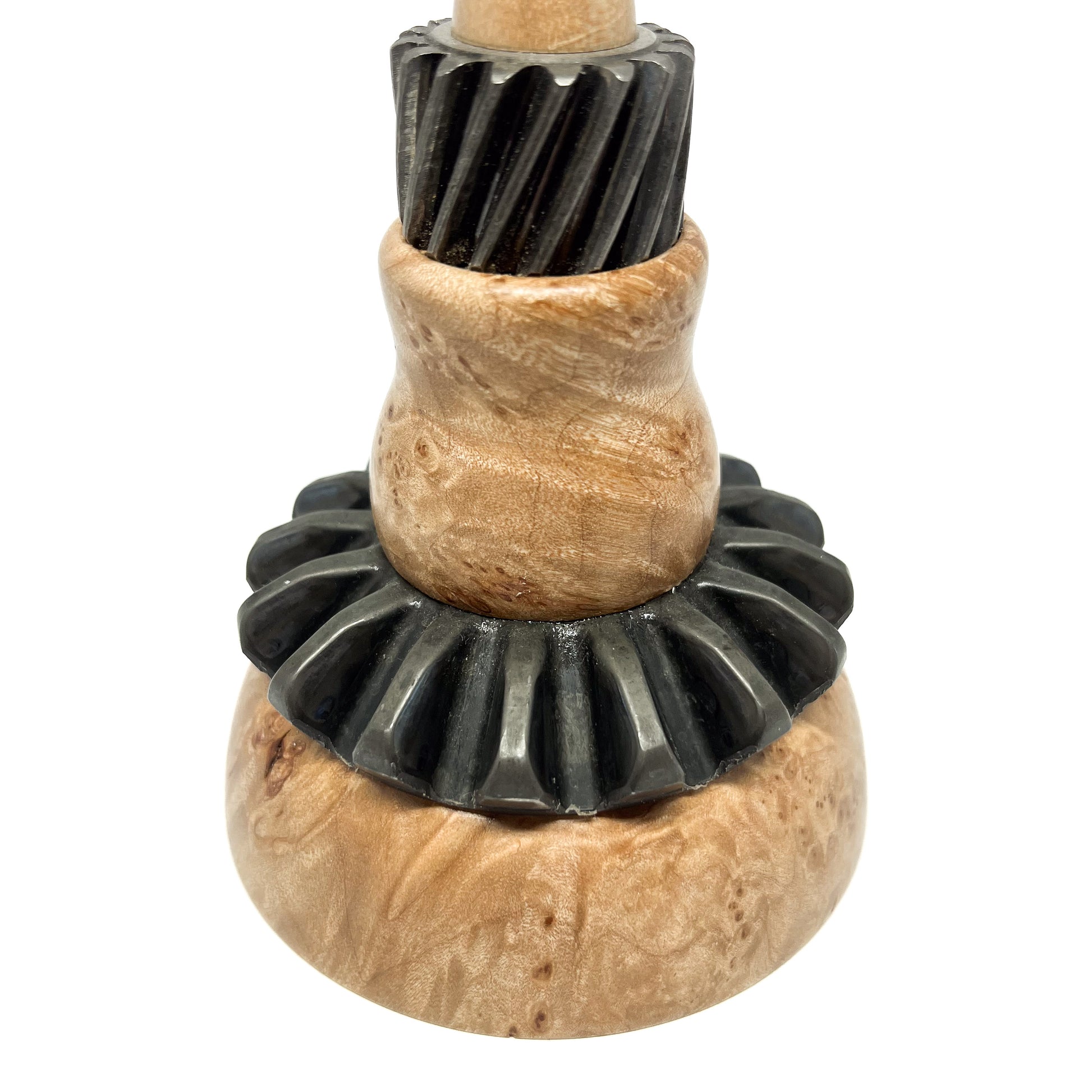 Close-up of a stacked mixed media spire sculpture with textured wood and black, ridged metal components.