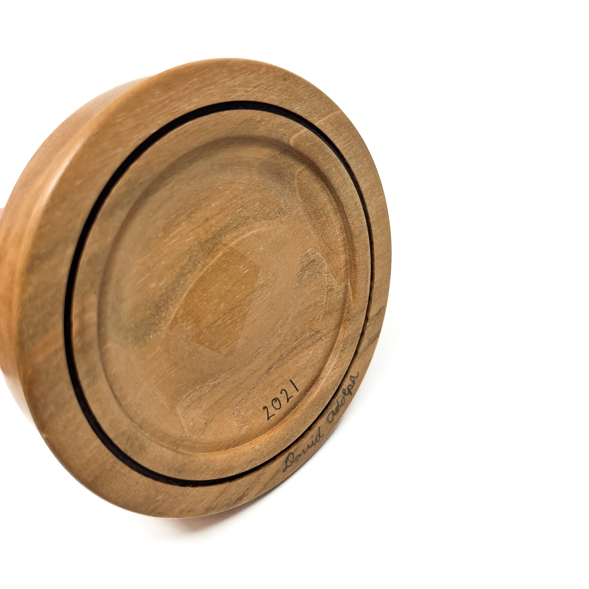 Bottom view of a round wooden base with concentric circles and a handwritten signature "David Adolph 2021".