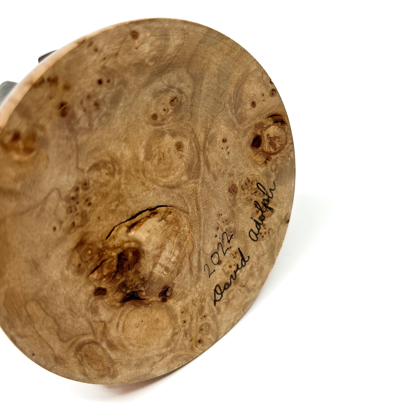 Close-up of the textured wooden base of a sculpture with a handwritten signature "David Adolph 2022".