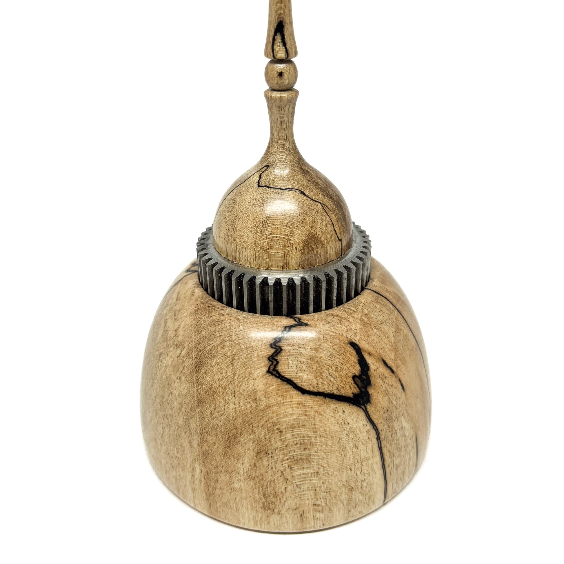 Close-up of a small wood spire sculpture with a textured metal ring and a tall, slender, detailed spire.