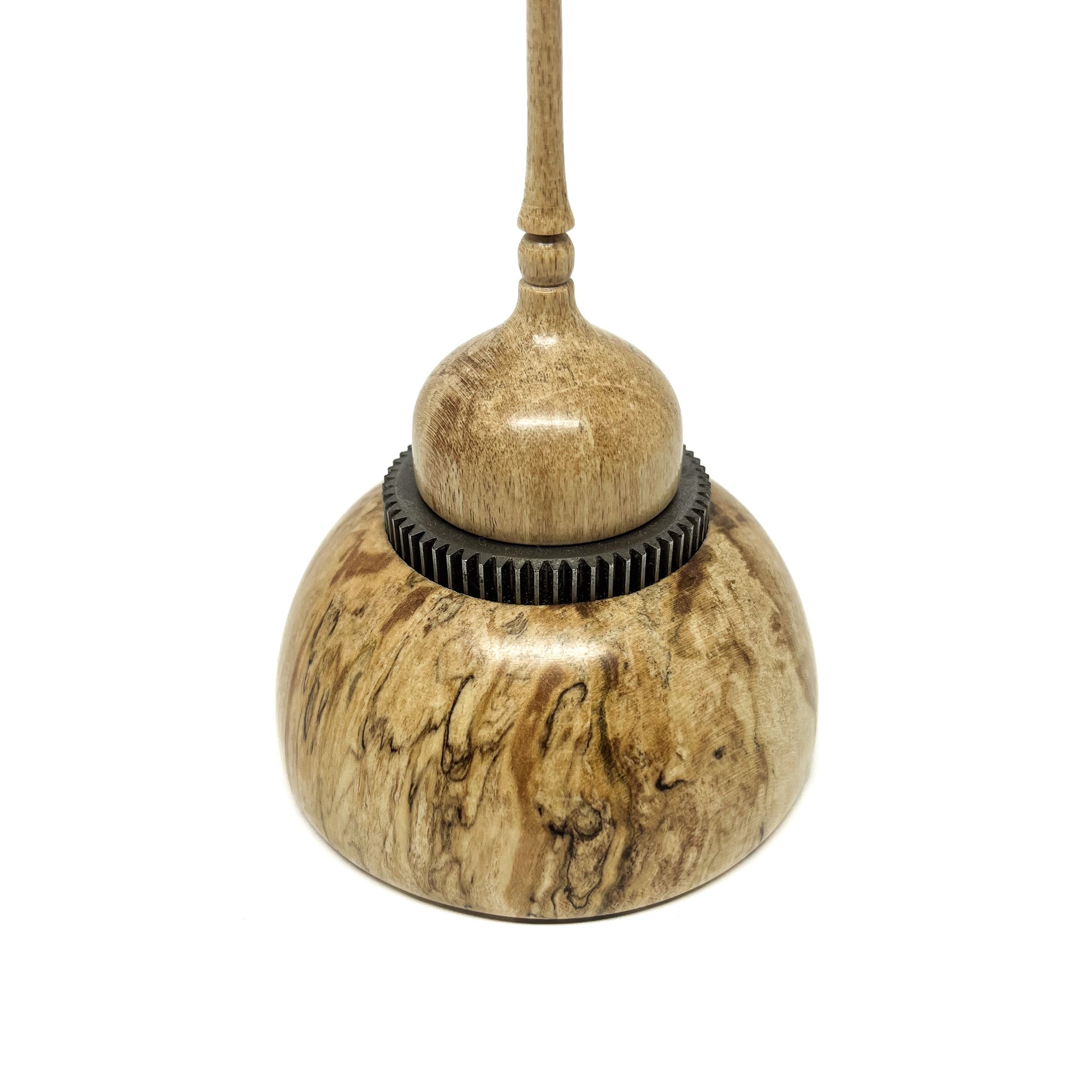 Close-up of a small wood spire sculpture with a textured dark ring and a slender, detailed spire.