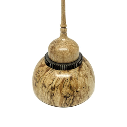 Close-up of a small wood spire sculpture with a textured dark ring and a slender, detailed spire.