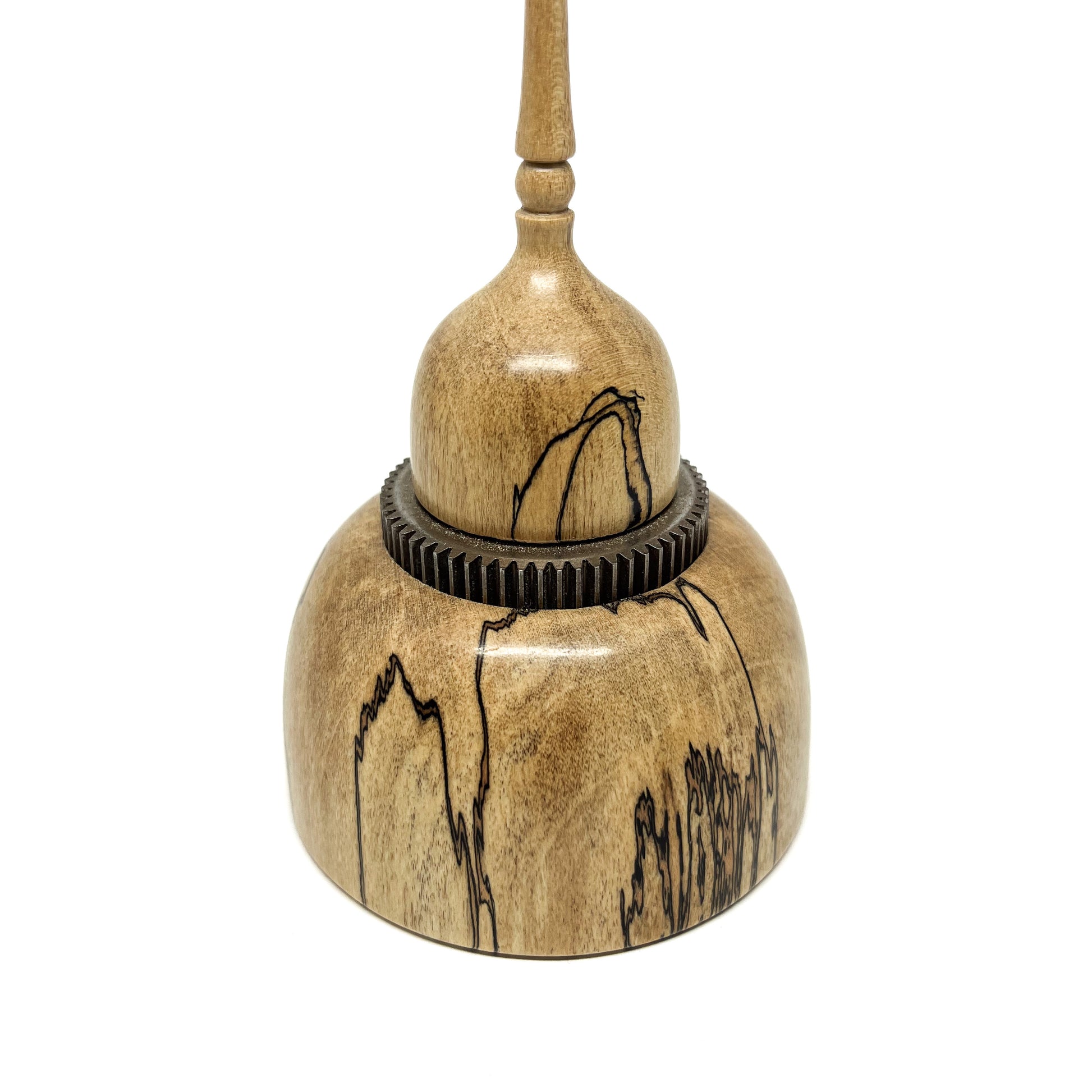 Close-up of a small wood spire sculpture with a dark, textured ring and a tall, slender, detailed spire.