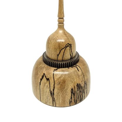 Close-up of a small wood spire sculpture with a dark, textured ring and a tall, slender, detailed spire.