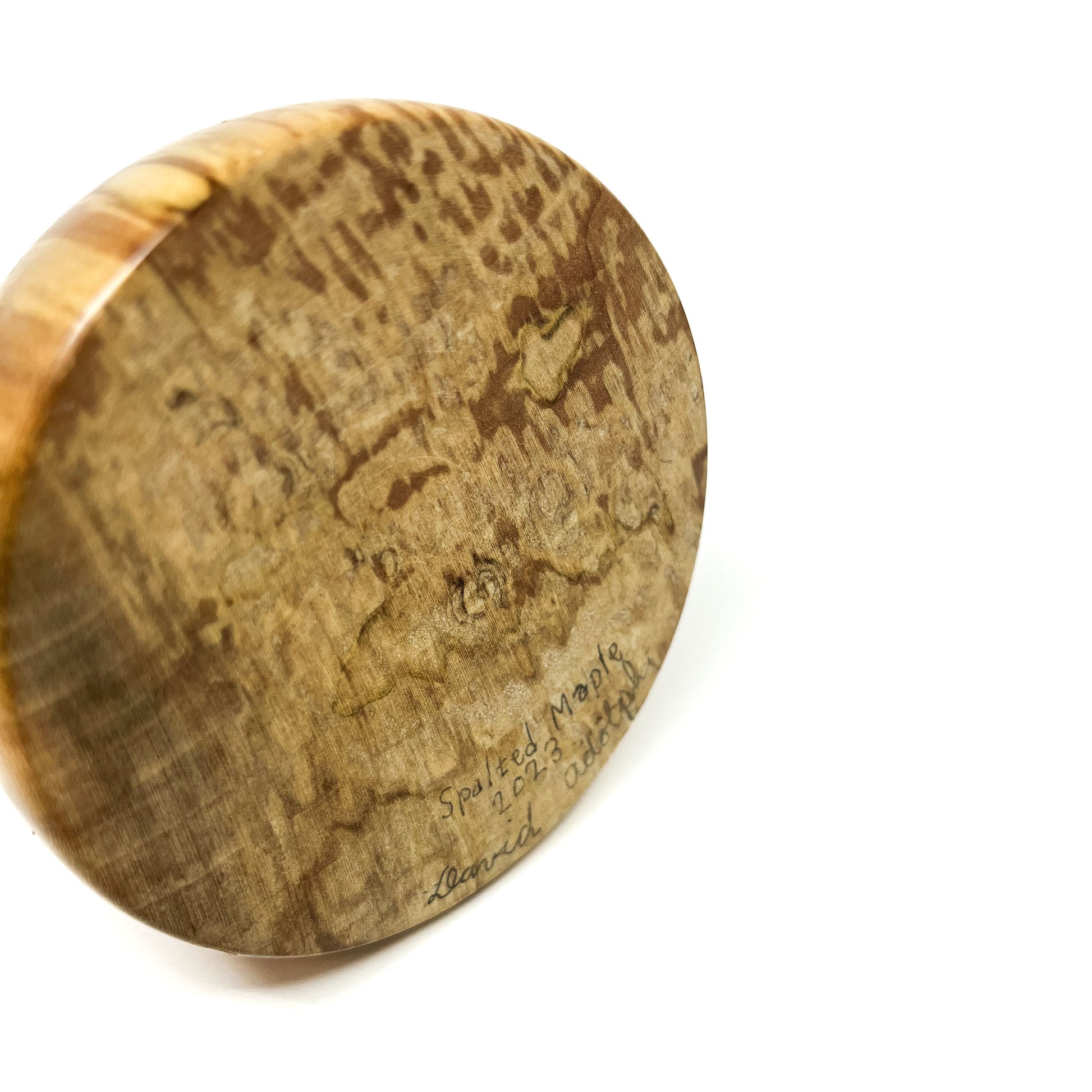 Close-up of the textured wood base of a sculpture signed "Spalted Maple 2023 David Adolph".
