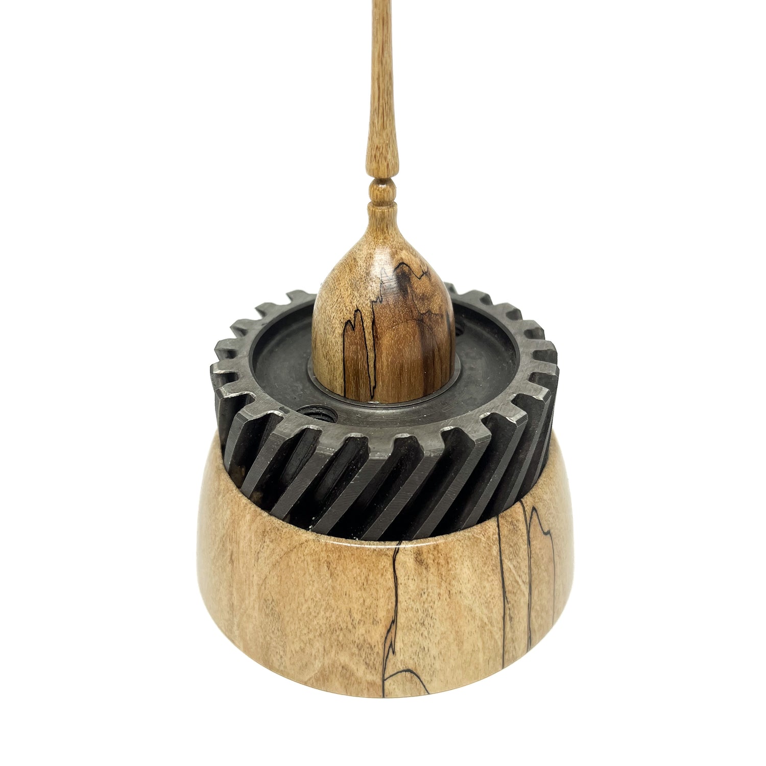 Close-up of a small wood spire sculpture by David Adolph with a large, dark cog-like ring and a slender, detailed spire.