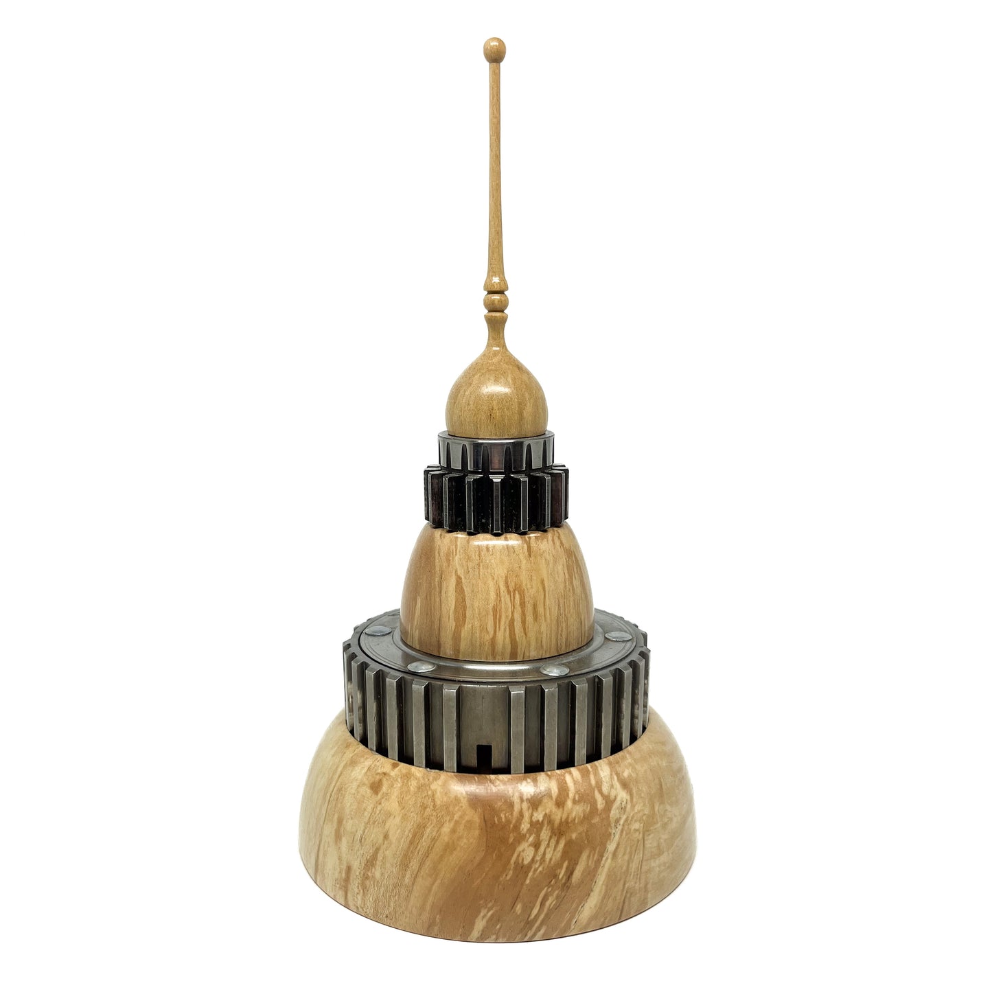Stacked wood spire sculpture by David Adolph with multiple dark, cog-like rings and a tall, slender, topped spire.