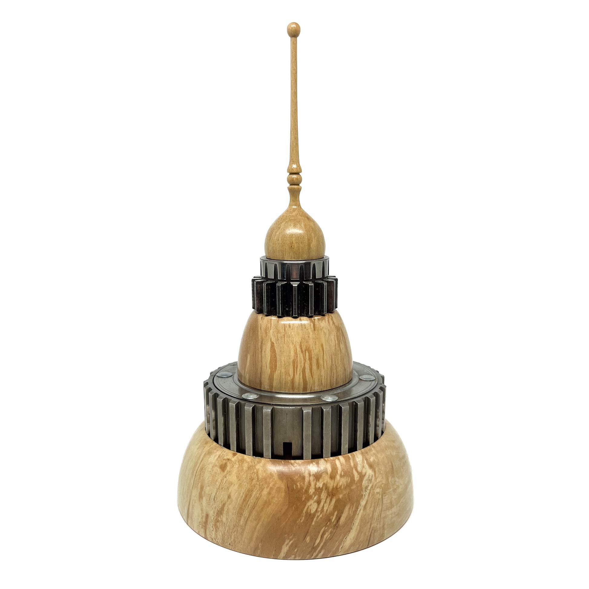 Stacked wood spire sculpture by David Adolph with multiple dark, cog-like rings and a tall, slender, topped spire.