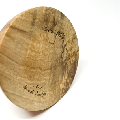 Close-up of the textured wood base of a sculpture signed "Spalted Maple 2023 David Adolph".